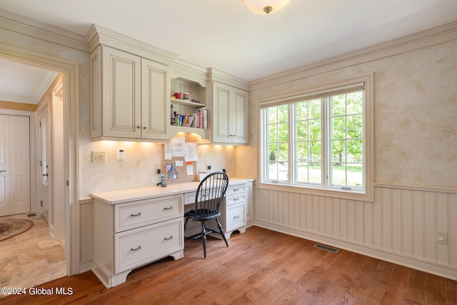 office area featuring a wainscoted wall, built in study area, light wood-style floors, and visible vents