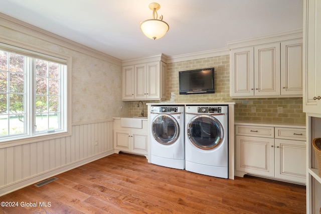 washroom featuring visible vents, washing machine and dryer, light wood-style flooring, cabinet space, and a sink