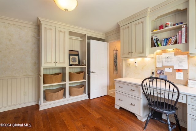 office space featuring dark wood finished floors, built in desk, wainscoting, and crown molding