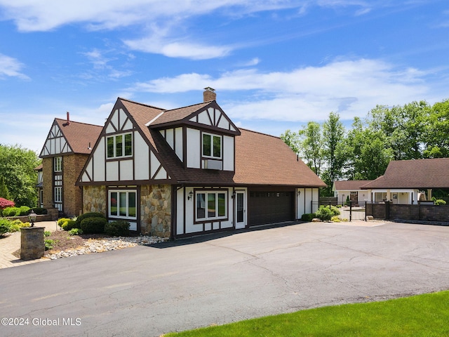 view of front of home featuring fence, stucco siding, a chimney, a garage, and stone siding