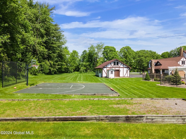 view of sport court with basketball hoop, a yard, and fence