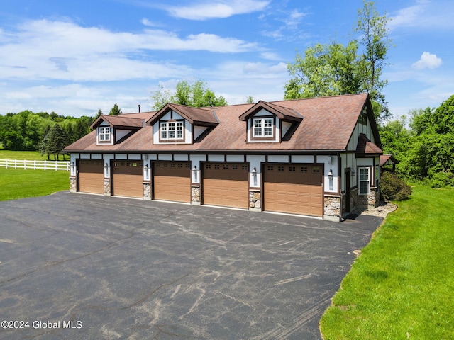 view of front of home featuring a front lawn, a garage, fence, and stone siding