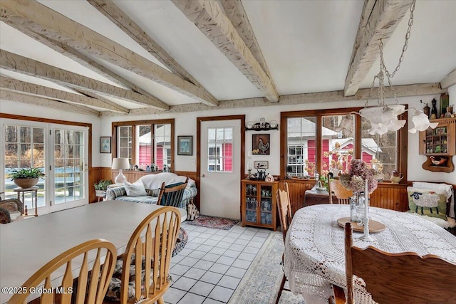 dining area featuring light tile patterned floors, a wainscoted wall, and beamed ceiling