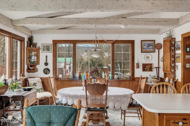 dining area featuring lofted ceiling with beams and wainscoting