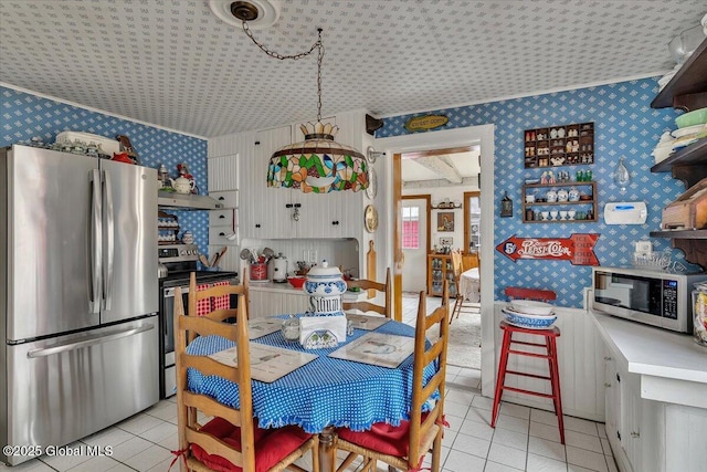 kitchen with wallpapered walls, light countertops, light tile patterned floors, and appliances with stainless steel finishes