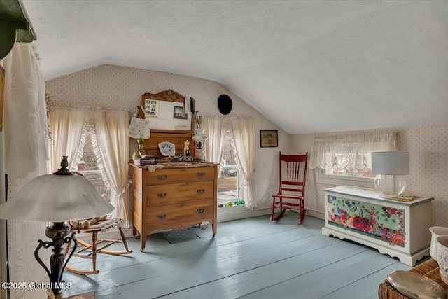 sitting room with a textured ceiling, wallpapered walls, wood-type flooring, and vaulted ceiling