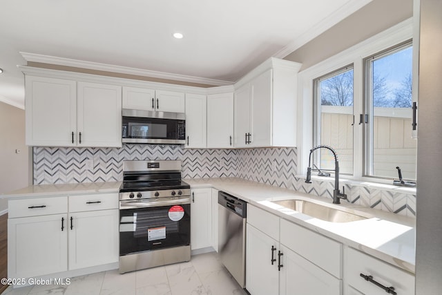 kitchen featuring a sink, ornamental molding, stainless steel appliances, white cabinets, and marble finish floor