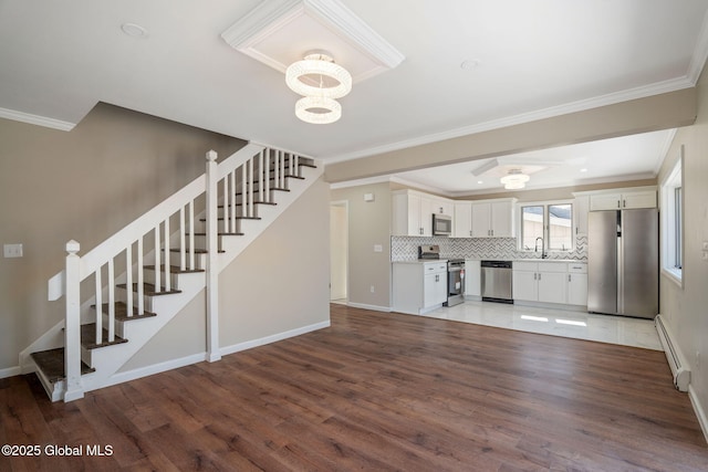 unfurnished living room featuring a notable chandelier, baseboard heating, wood finished floors, and stairs