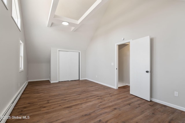 spare room with a wealth of natural light, baseboard heating, and wood finished floors