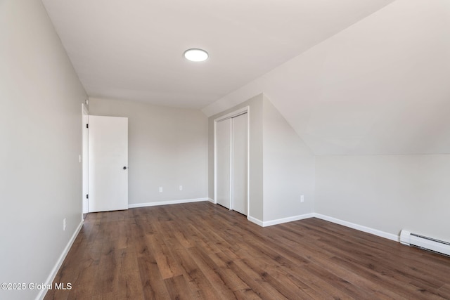 additional living space with a baseboard radiator, baseboards, dark wood finished floors, and vaulted ceiling