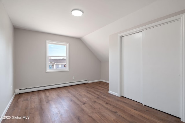 additional living space featuring baseboards, wood finished floors, lofted ceiling, and a baseboard radiator