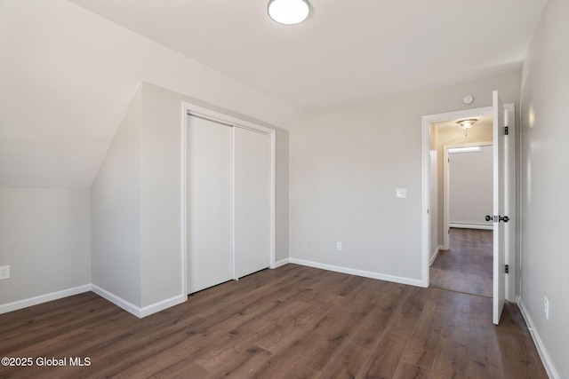 unfurnished bedroom featuring a closet, dark wood-type flooring, and baseboards