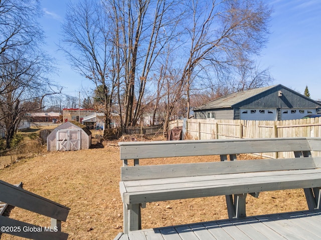 view of yard featuring fence, an outbuilding, a deck, and a shed