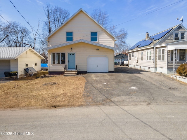 view of front of house featuring aphalt driveway, a garage, entry steps, and fence