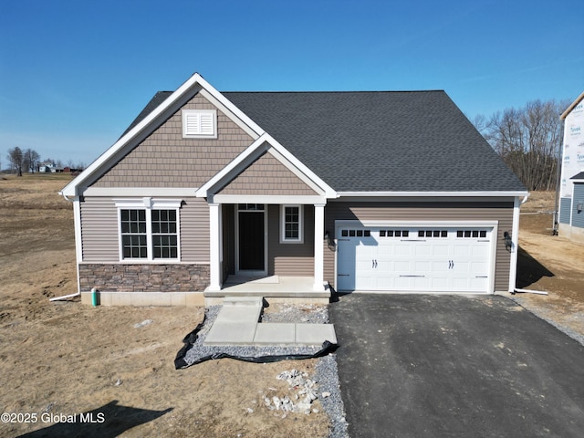 craftsman-style home featuring stone siding, driveway, and an attached garage