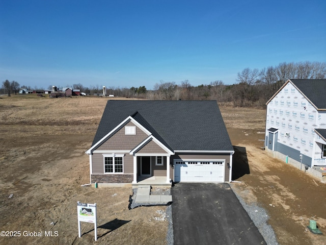 view of front of property with aphalt driveway, a garage, and stone siding
