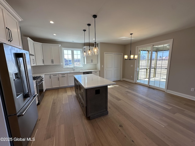 kitchen with light wood-style flooring, appliances with stainless steel finishes, light countertops, and baseboards
