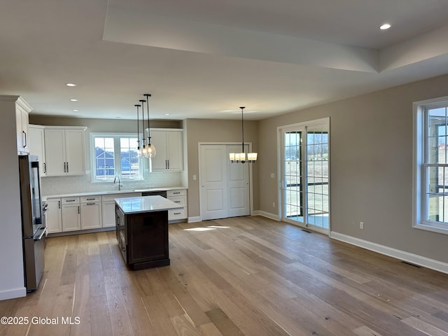 kitchen with light wood finished floors, baseboards, light countertops, decorative backsplash, and fridge
