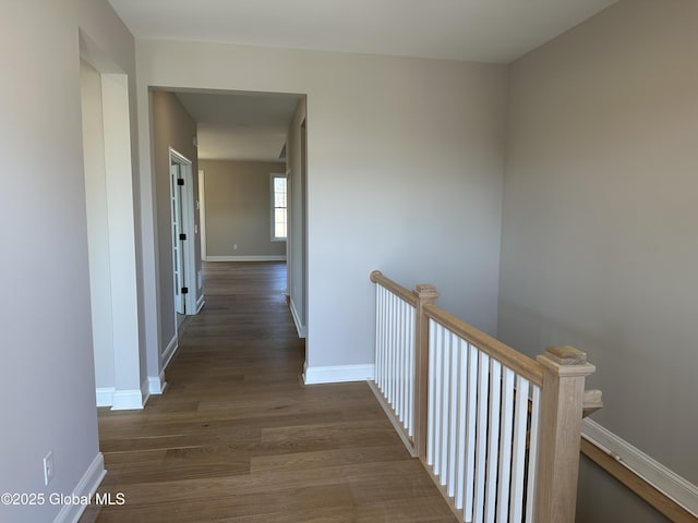 hall featuring wood finished floors, an upstairs landing, and baseboards