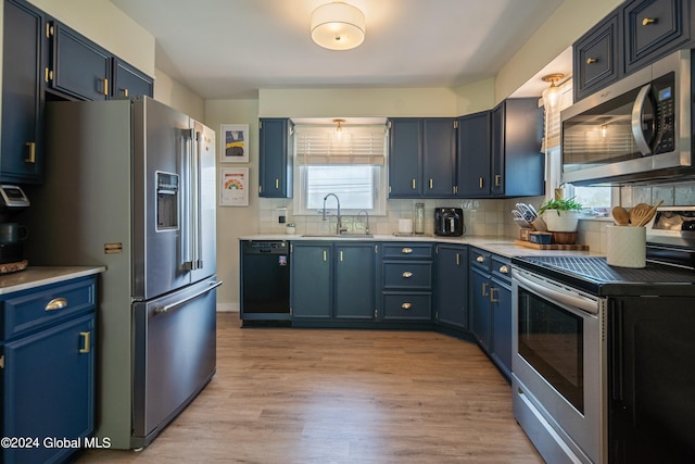 kitchen with light countertops, light wood-style floors, stainless steel appliances, blue cabinets, and a sink