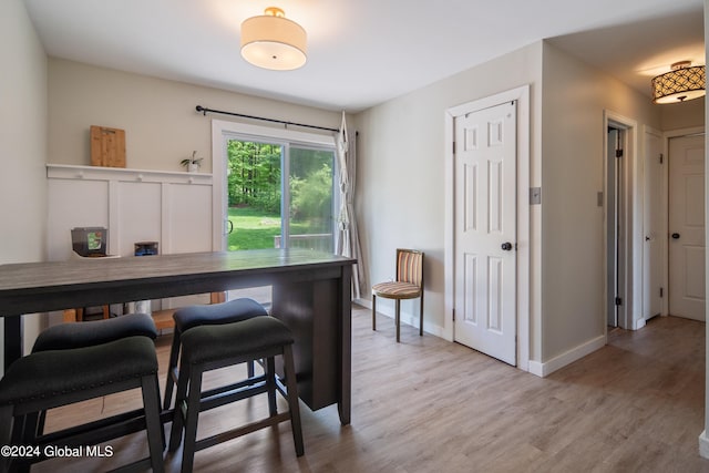 dining space with baseboards and light wood-style flooring