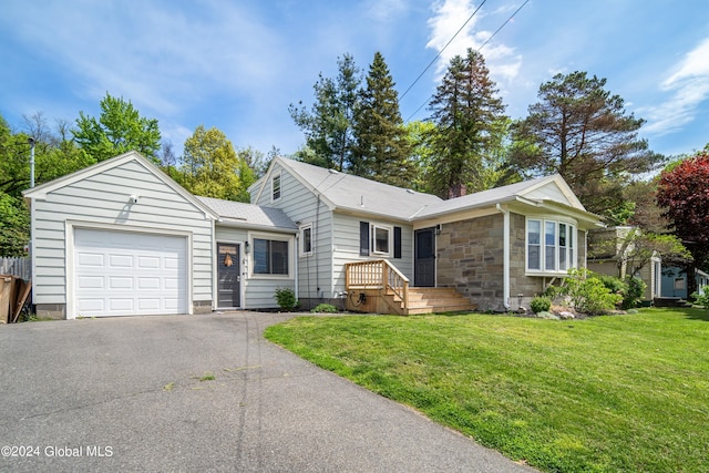 ranch-style home featuring stone siding, an attached garage, driveway, and a front lawn