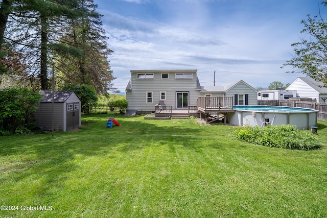 rear view of property with an outbuilding, a deck, a yard, a storage shed, and an outdoor pool