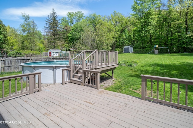 deck with a storage unit, an outbuilding, a fenced backyard, a yard, and a fenced in pool