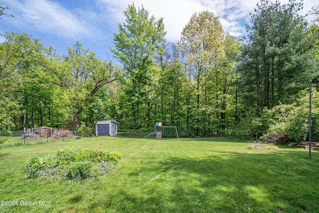 view of yard with an outdoor structure, a playground, and a shed