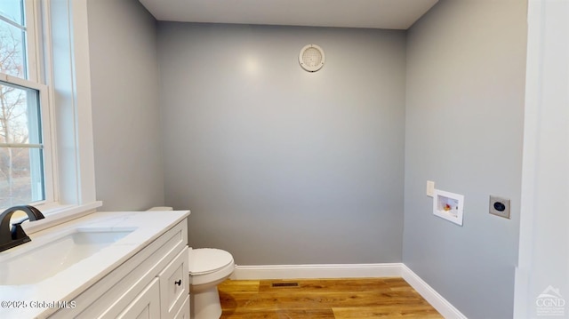 bathroom featuring visible vents, baseboards, toilet, wood finished floors, and vanity