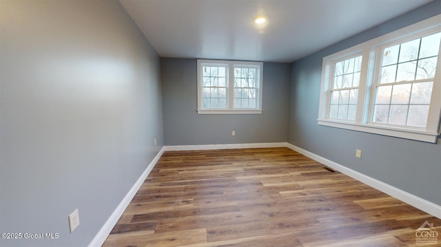 spare room featuring wood finished floors, a healthy amount of sunlight, and baseboards