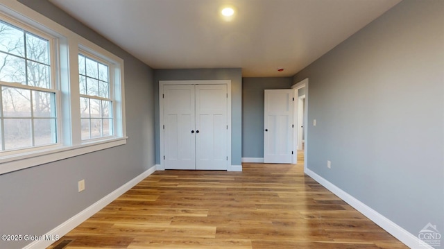 unfurnished bedroom featuring baseboards, a closet, and light wood-type flooring