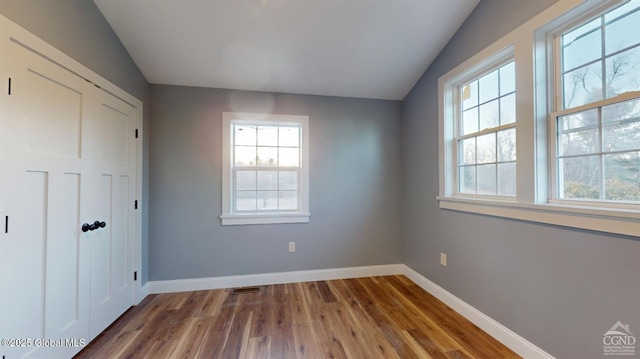 unfurnished bedroom featuring a closet, baseboards, visible vents, and wood finished floors