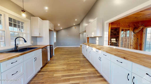 kitchen featuring light wood finished floors, wooden counters, a sink, white cabinets, and stainless steel dishwasher