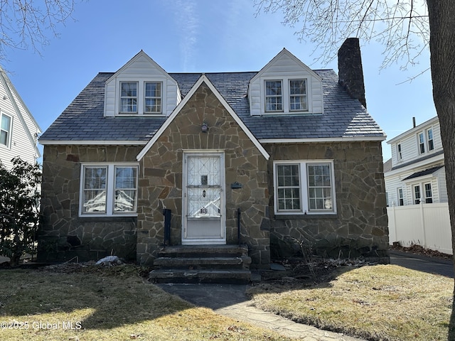 view of front of house with stone siding, fence, a chimney, and entry steps