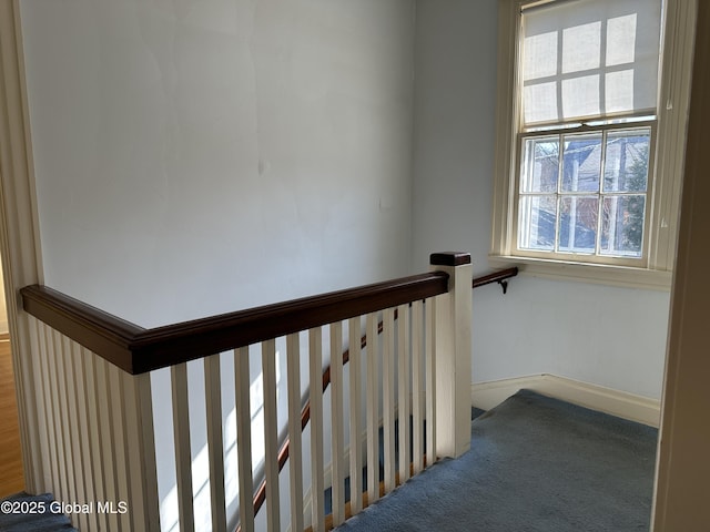 corridor with an upstairs landing, baseboards, and carpet floors