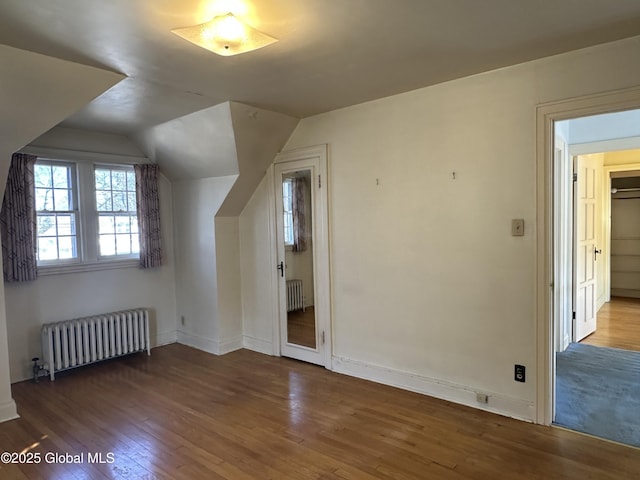 bonus room featuring vaulted ceiling, radiator heating unit, baseboards, and hardwood / wood-style flooring