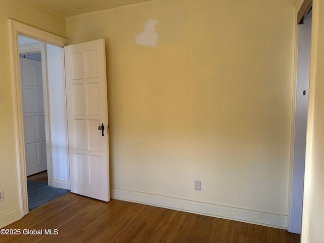 spare room featuring baseboards and wood finished floors