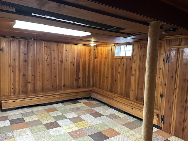 basement featuring light floors and wood walls