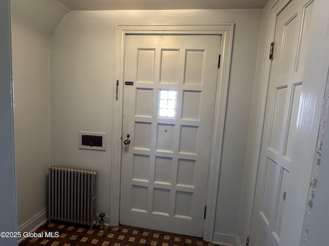 doorway with radiator heating unit, baseboards, and dark floors