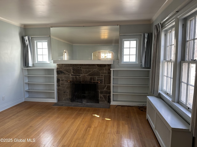 unfurnished living room with wood-type flooring, radiator, a fireplace, and crown molding