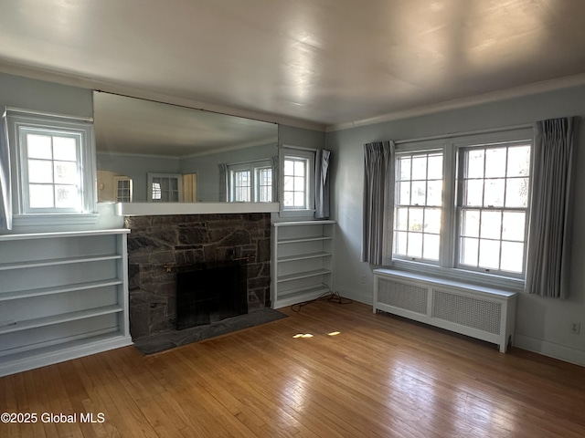 unfurnished living room featuring hardwood / wood-style flooring, crown molding, radiator, and a fireplace