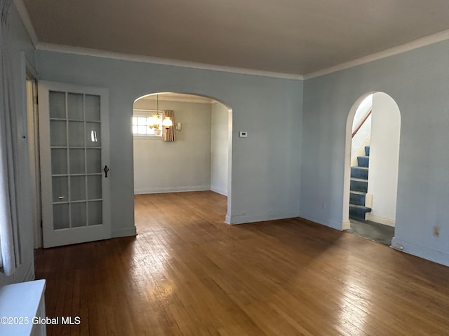 unfurnished room with arched walkways, an inviting chandelier, wood-type flooring, and crown molding