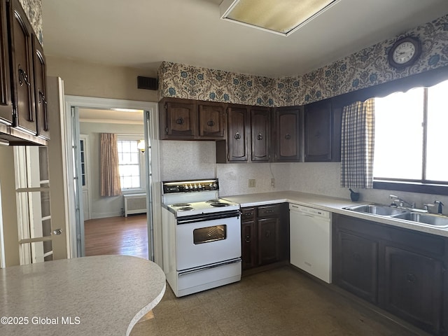 kitchen with dark brown cabinets, radiator, tile patterned floors, white appliances, and a sink