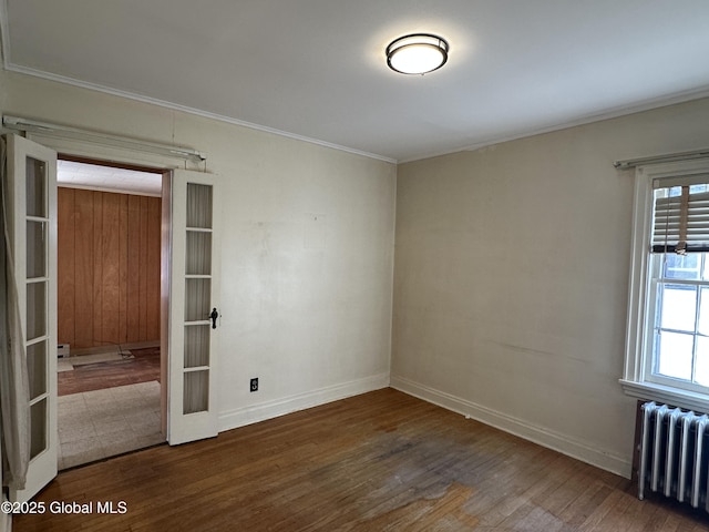 empty room with a wealth of natural light, radiator, french doors, and wood finished floors