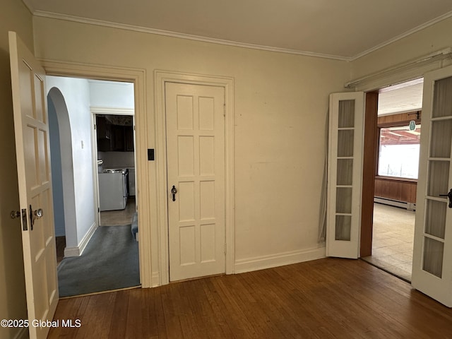 unfurnished room featuring baseboards, dark wood finished floors, arched walkways, ornamental molding, and baseboard heating