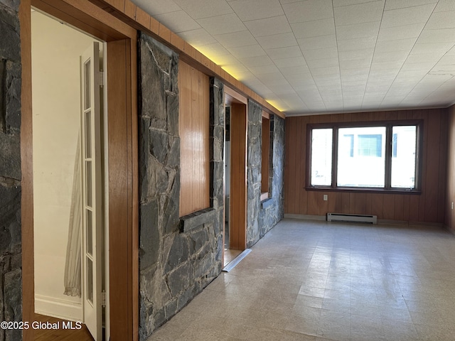 spare room featuring light floors, wood walls, and baseboard heating