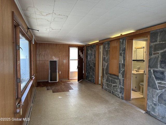 interior space featuring tile patterned floors, baseboard heating, wooden walls, and a sink