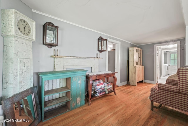 living area featuring baseboards, wood finished floors, and crown molding