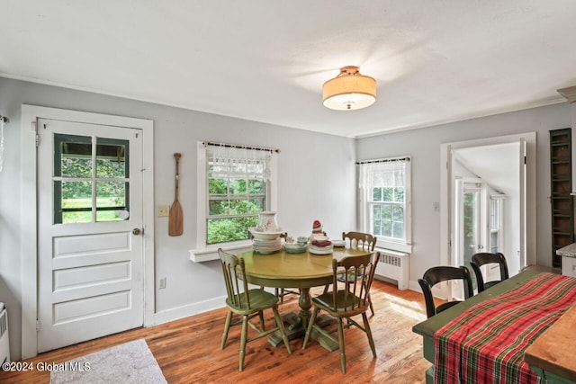 dining space featuring radiator heating unit, wood finished floors, and baseboards